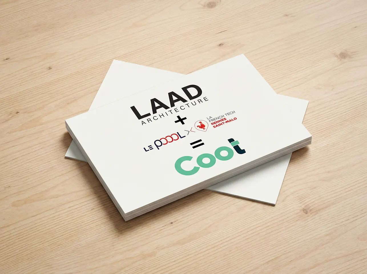 Pile de cartes de visite sur une surface en bois clair avec les logos et textes «LAAD ARCHITECTURE + Le Poool x French Tech Rennes Saint-Malo = Coot».