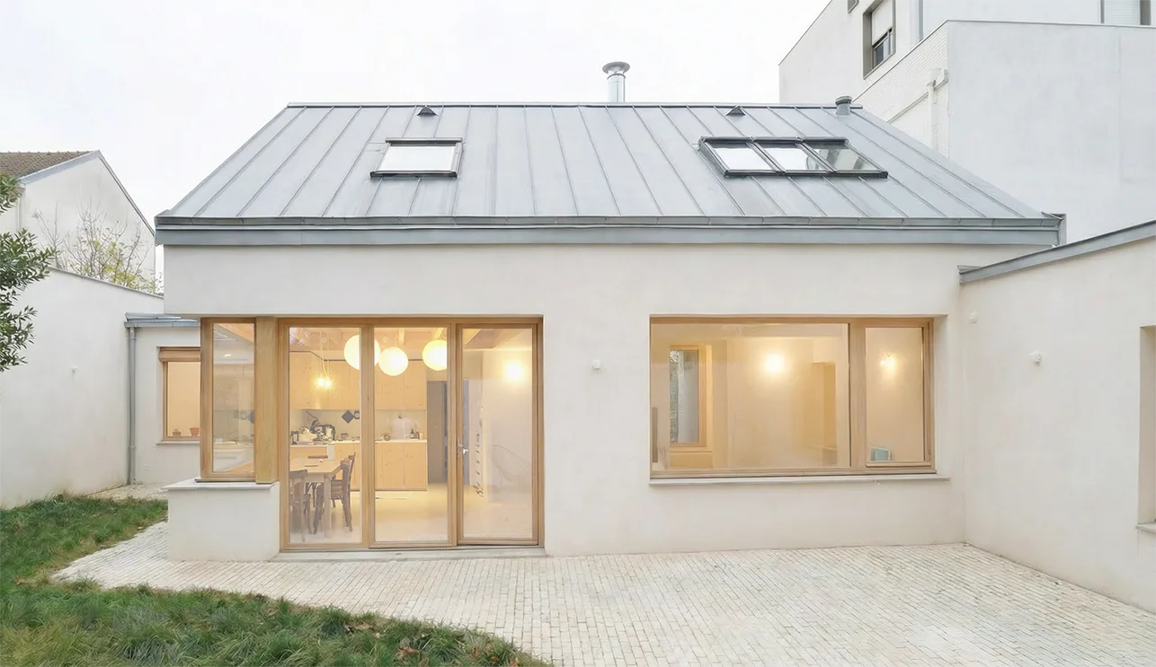 Vignette de la maison #LOTI, façade sur jardin en enduit clair et menuiseries bois.