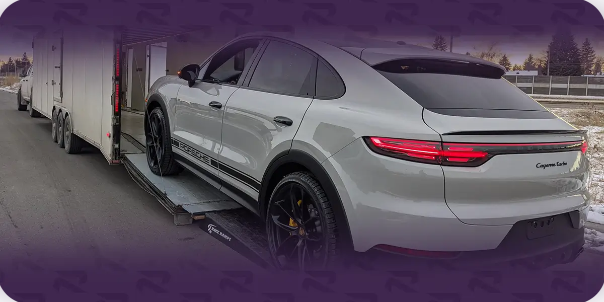 Silver Porsche Cayenne Turbo Coupe on a loading ramp at the rear of an enclosed transport trailer