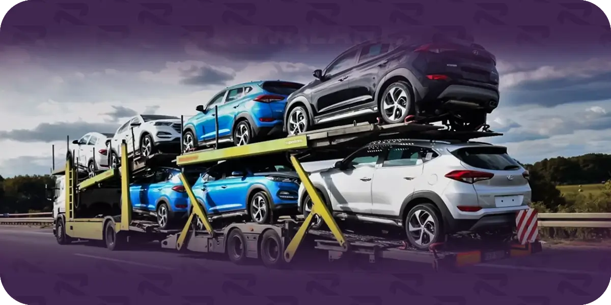 An open car carrier loaded with SUVs on two decks, traveling on a highway under a cloudy sky.
