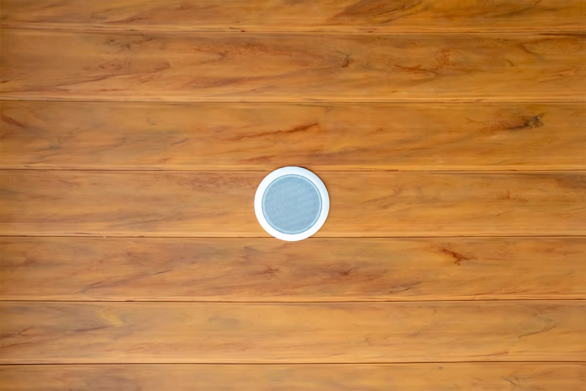 A speaker installed on a ceiling with wooden paneling for a home.