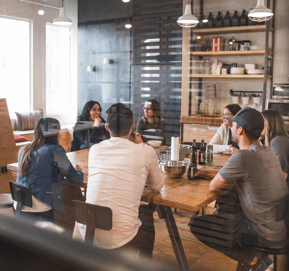 Group of people sitting around wooden table in modern kitchen space