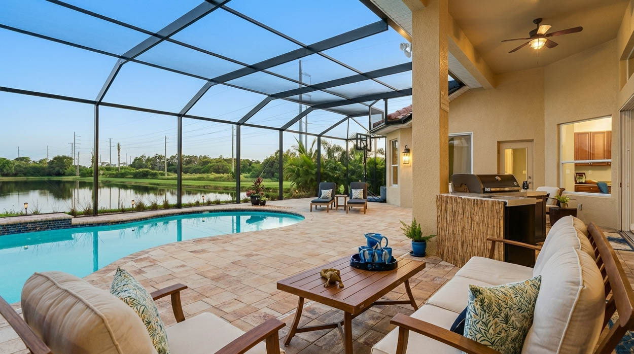 Custom pool screen enclosure with outdoor kitchen and seating installed by licensed Florida pool enclosure builders.