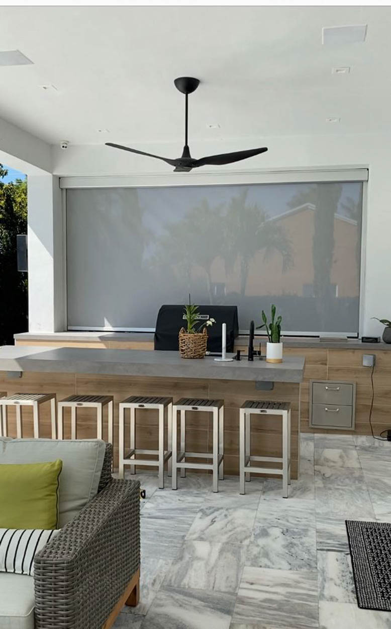 Motorized screen enclosure protecting an outdoor kitchen and dining area, ideal for Florida homeowners looking to extend outdoor living year-round.