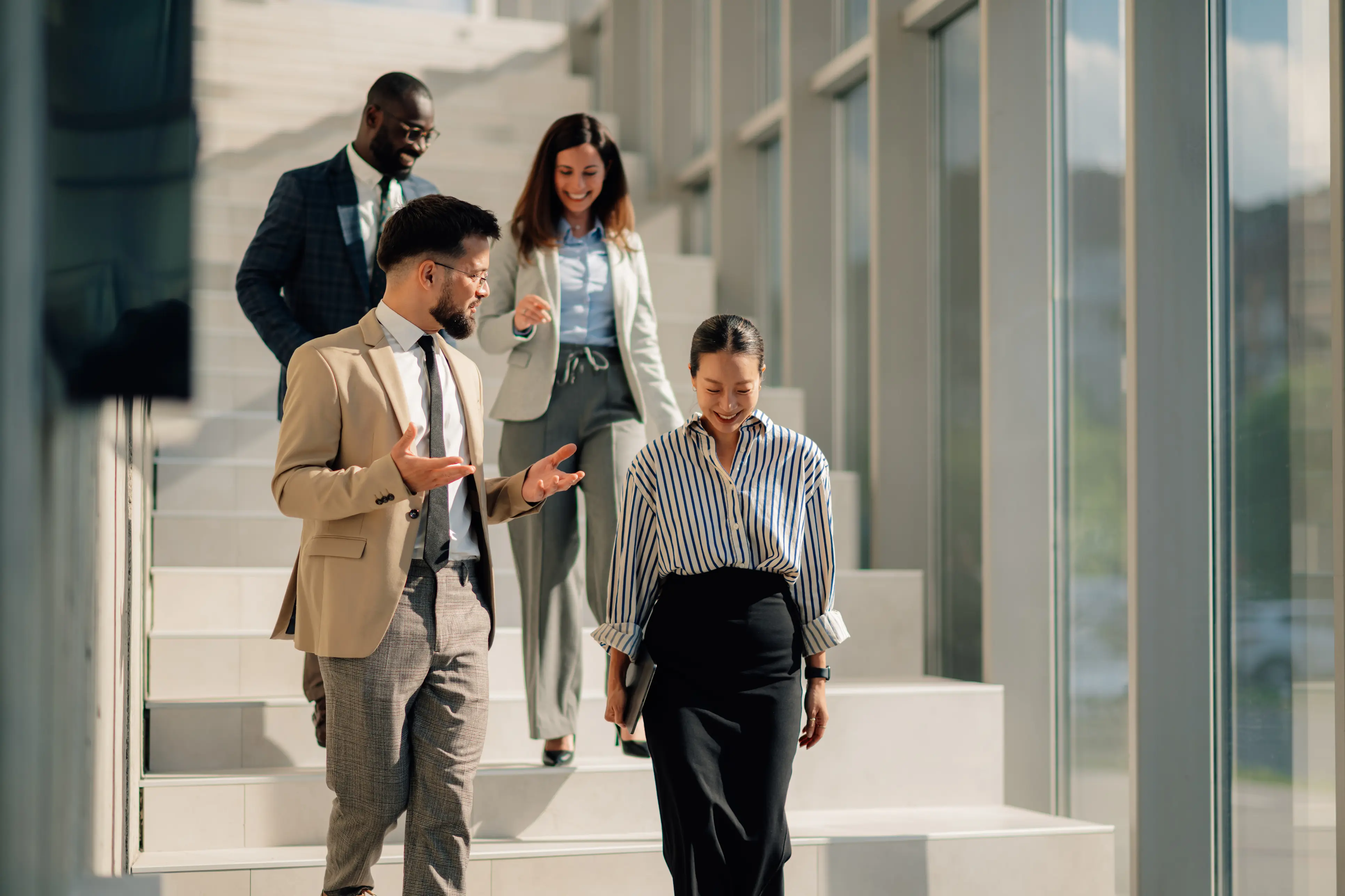Business team walking down bright office stairs discussing ideas.