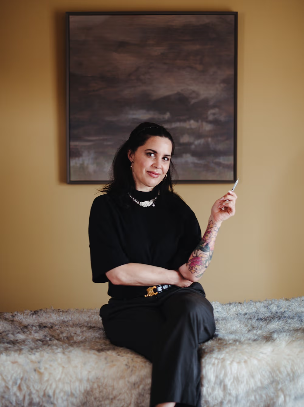 AmSPA professional with tattoo poses confidently in black, holding cosmetic tool