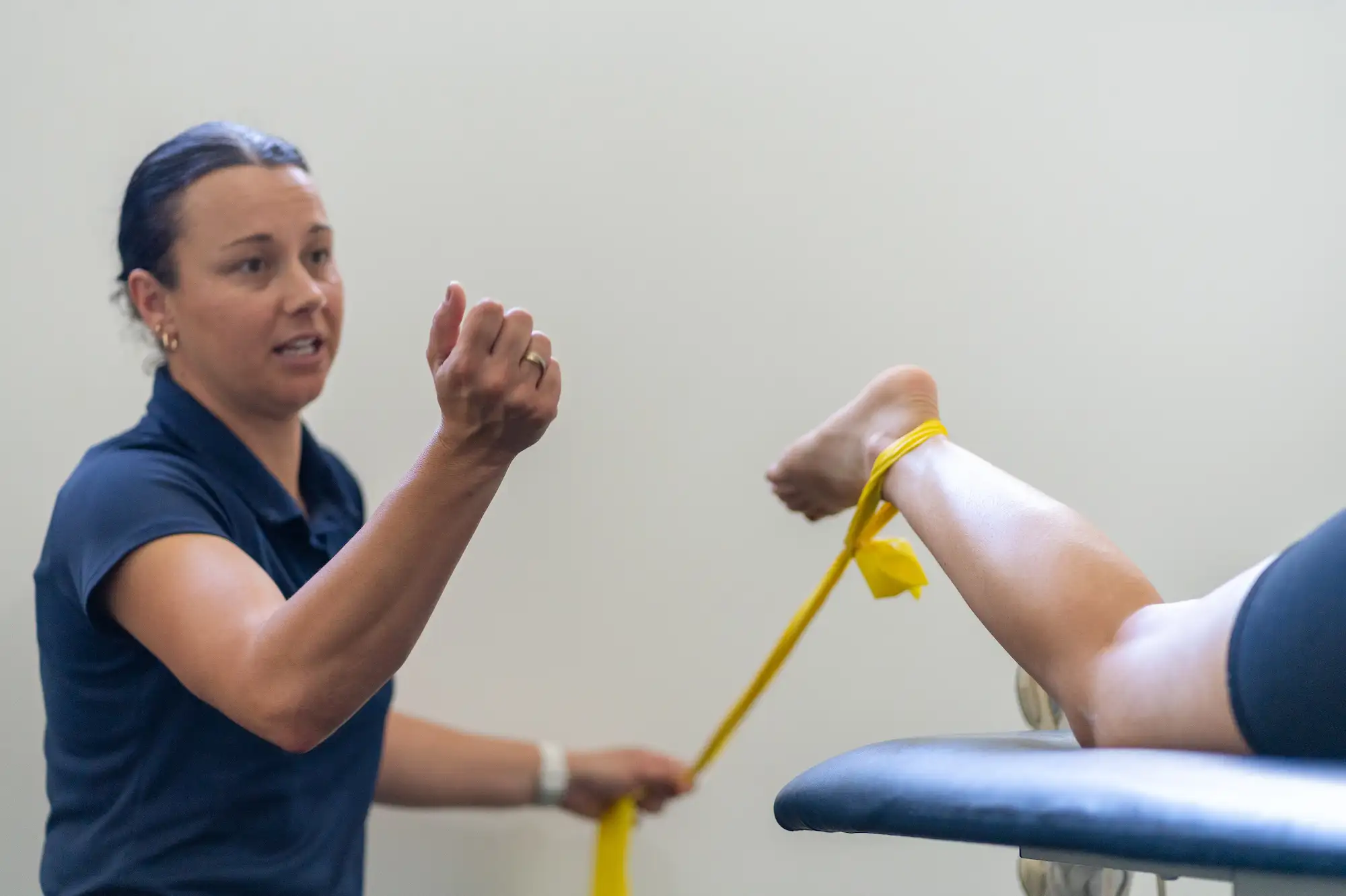 Therapist assisting a patient with a yellow resistance band exercise on their foot.