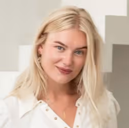 Jonge vrouw met lang blond haar en lichte make-up glimlacht naar de camera.