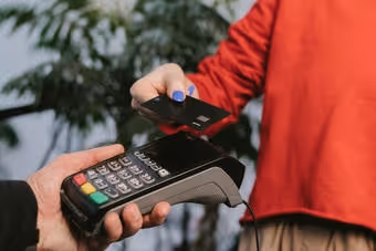 Person holding a credit card near a payment terminal to make a contactless payment.