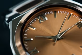 Close-up of a luxury wristwatch with rose gold face and metallic case showing minute and hour hands.
