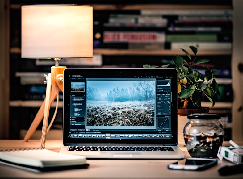 A Notepad, Phone, Potted Plant, and Laptop Featuring a Website Design Mid-Development 