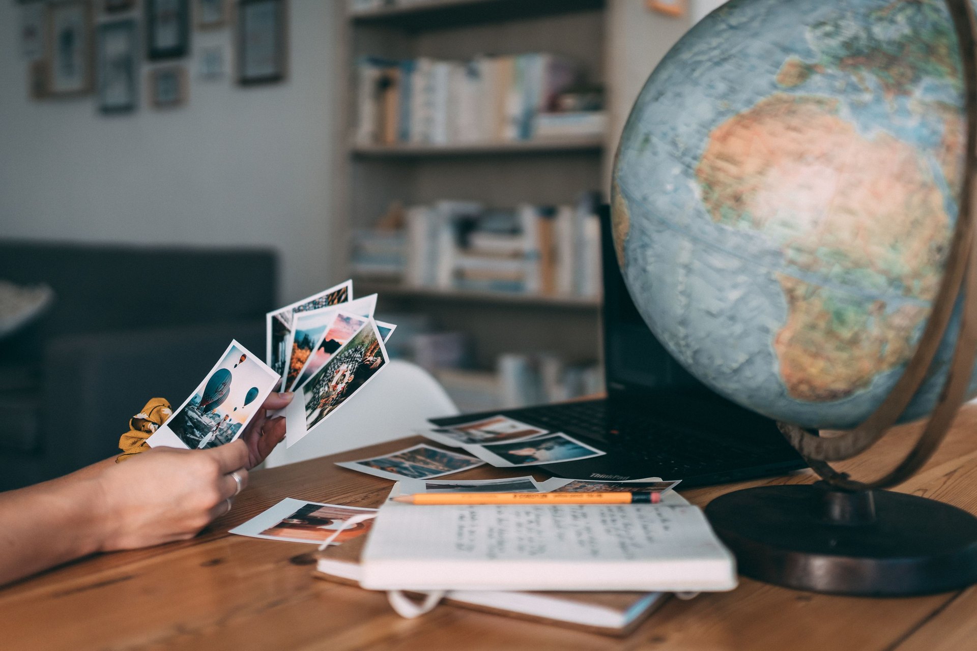 A globe, travel photos and a handwritten notebook on a desk, as vacation days are planned in Switzerland
