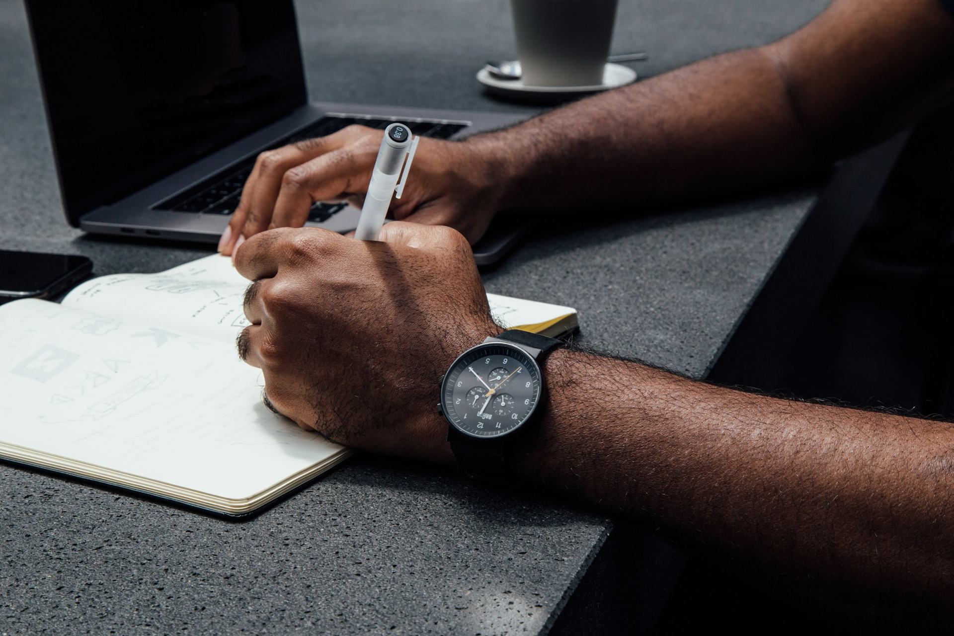 Wristwatch and notebook on a desk while working, hourly wage in Switzerland