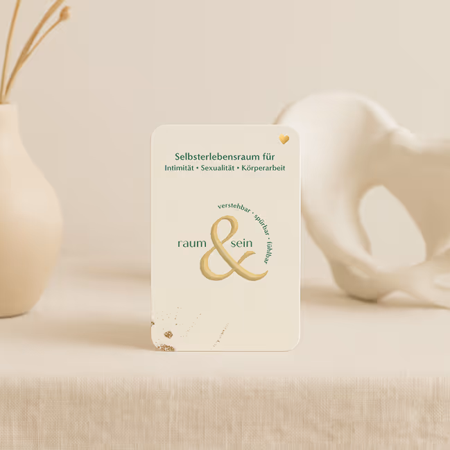 Karte mit dem Schriftzug „Selbsterlebensraum für Intimität, Sexualität, Körperarbeit“ und „raum & sein“ auf einem hellen Hintergrund zwischen zwei beige Dekorationsobjekten.