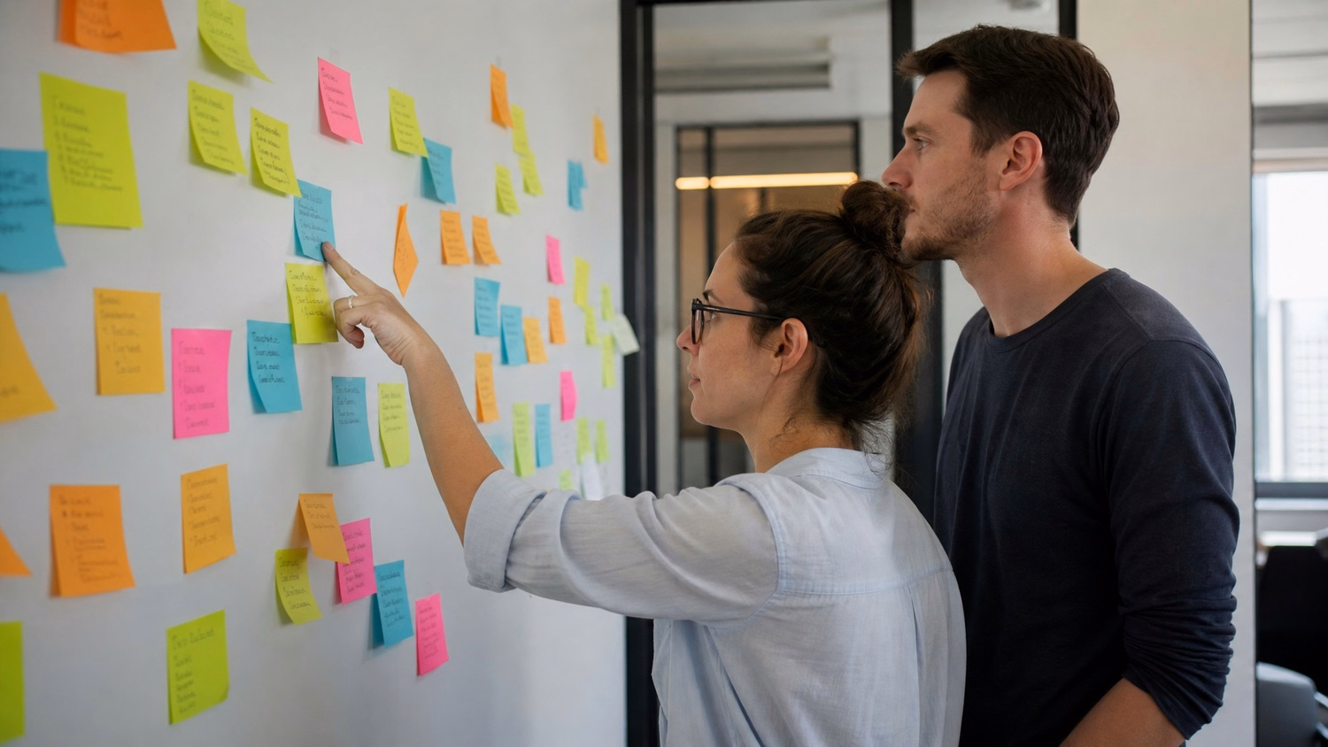 STICKY NOTE WALL An IT professional two people standing at a wall covered wi