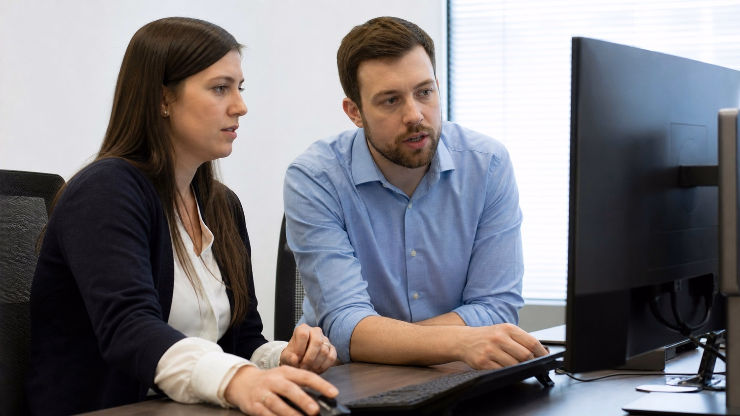 SIDE-BY-SIDE PAIR An IT professional two people seated side by side reviewin