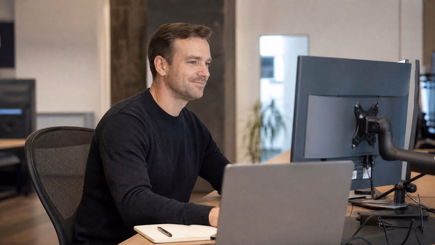 IT technician focused on laptop at workstation, notepad beside 67 chars
