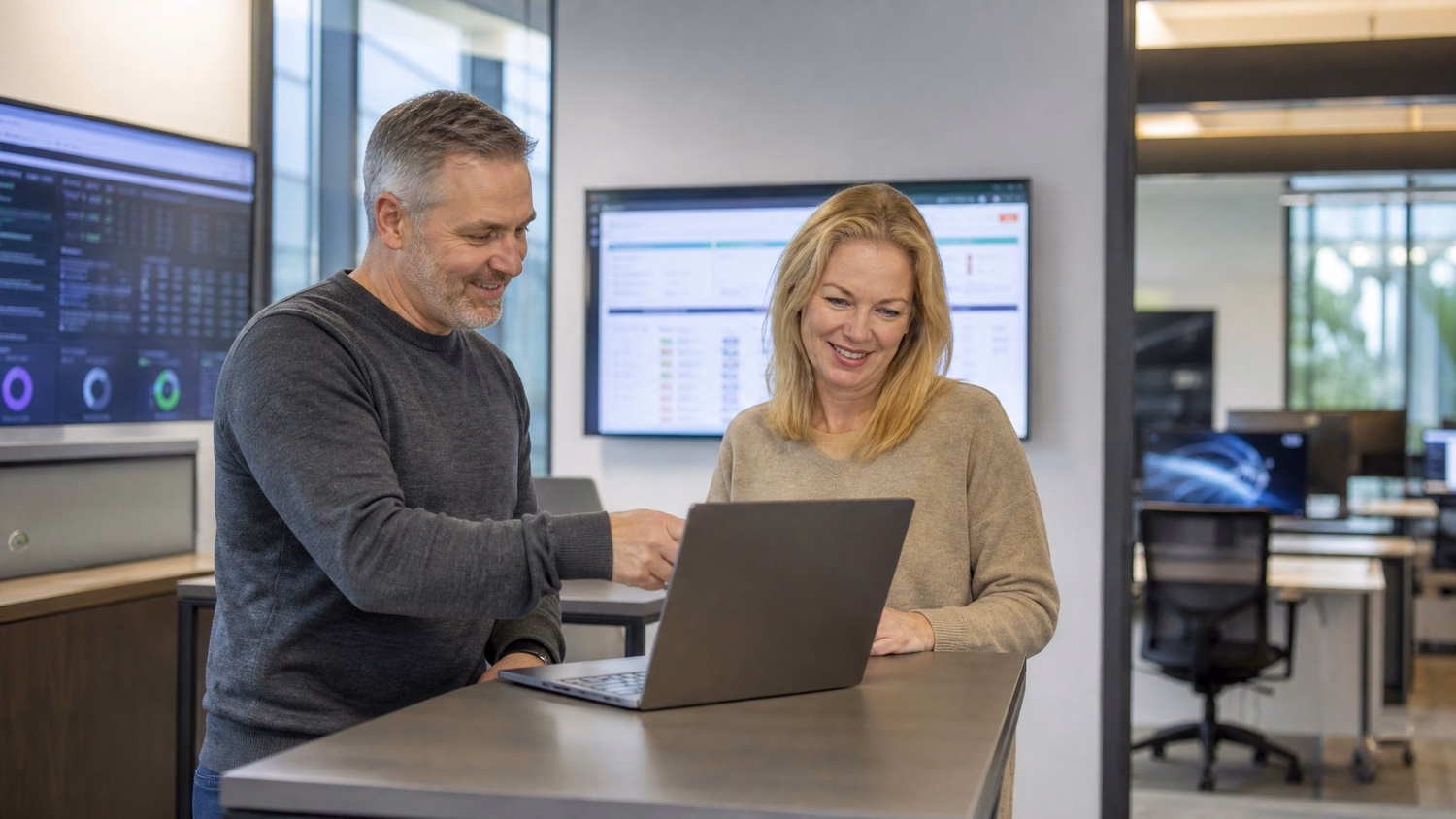 IT compliance audit team discusses laptop report at standing table