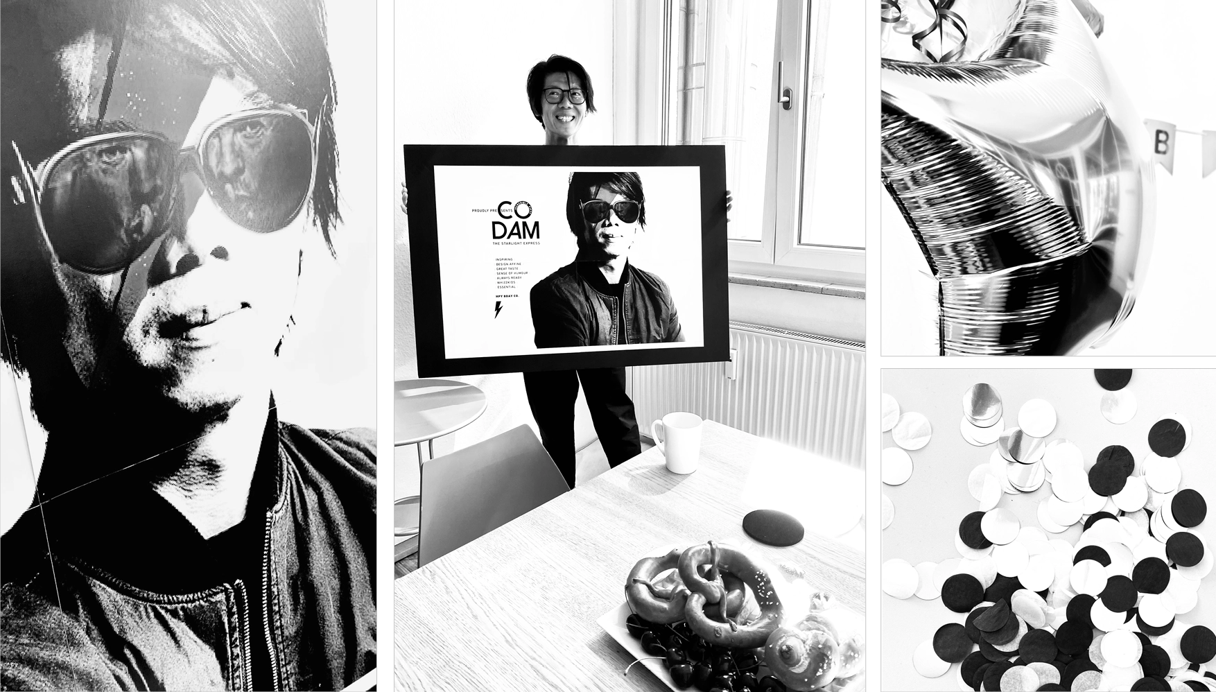 Person holding a framed poster featuring a man wearing sunglasses and a jacket, with a table showing pretzels, cherries, a mug, and a computer mouse, alongside star-shaped balloons and scattered confetti.