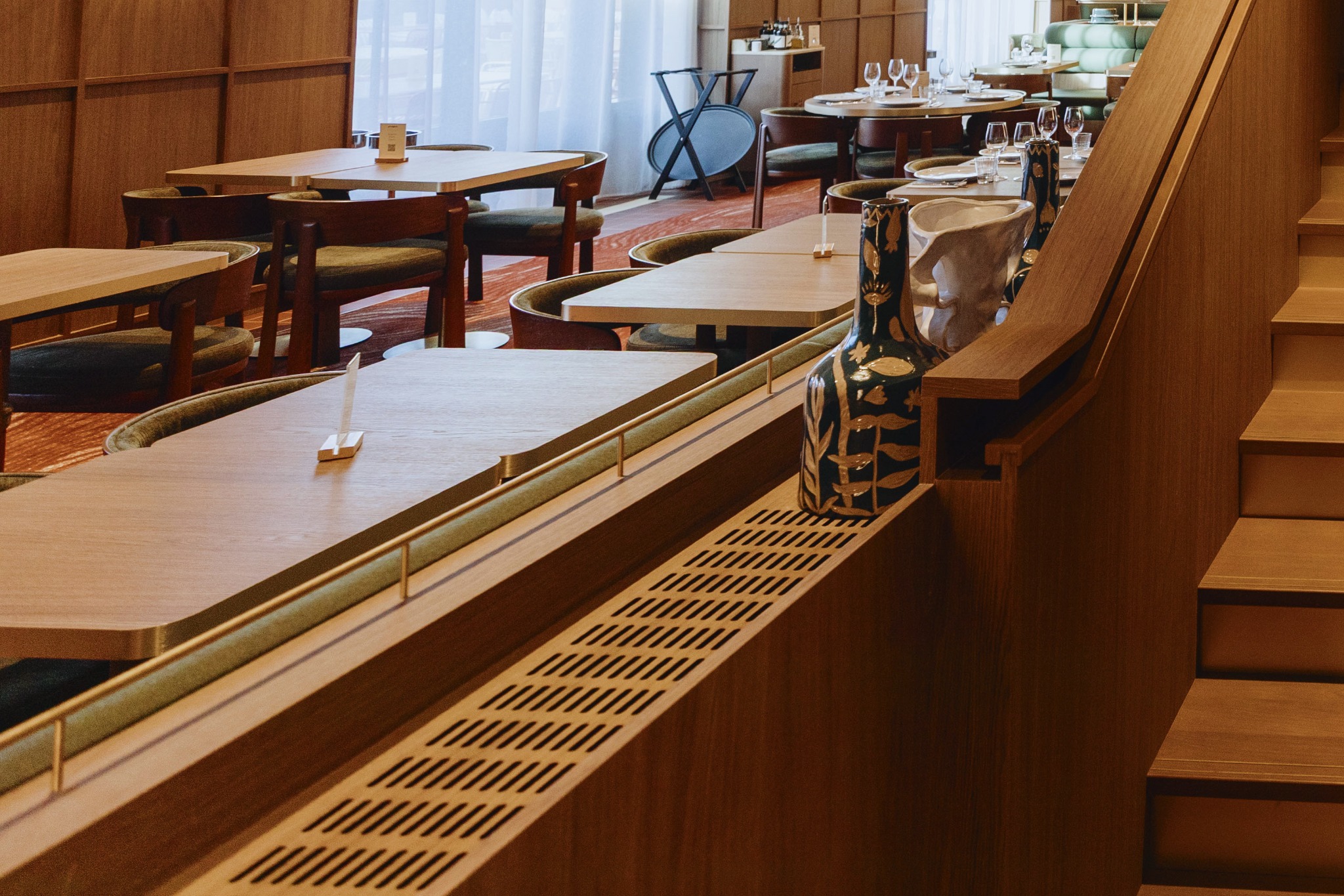 Vue rapprochée de la galerie en laiton brossé et de ses petits montants derrière une banquette de GRAPPA.