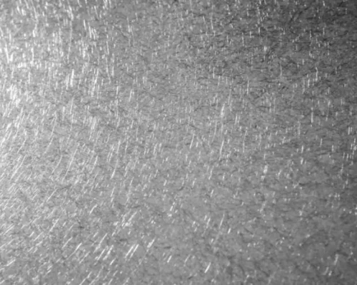 Exemple d’inox vibré à grain marqué, avec des traces de ponçage croisées et des reflets argentés.