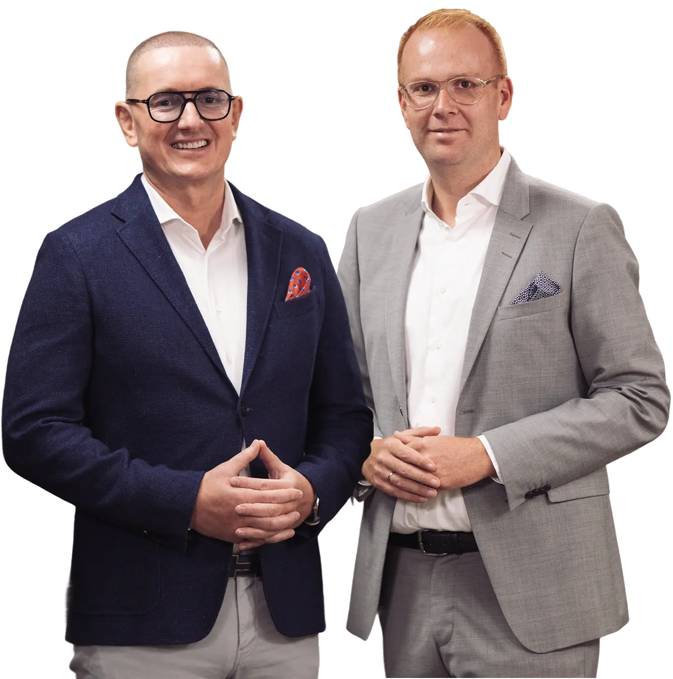 Zwei lächelnde Männer in Anzügen, einer mit dunkelblauem und der andere mit grauem Sakko, beide mit weißen Hemden und Einstecktüchern.