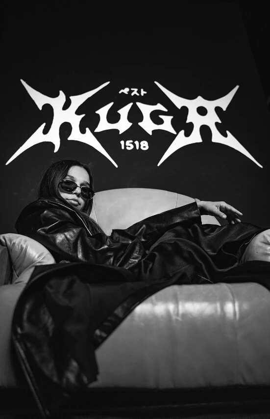 A woman sitting on a couch with a big Kuga sign above.