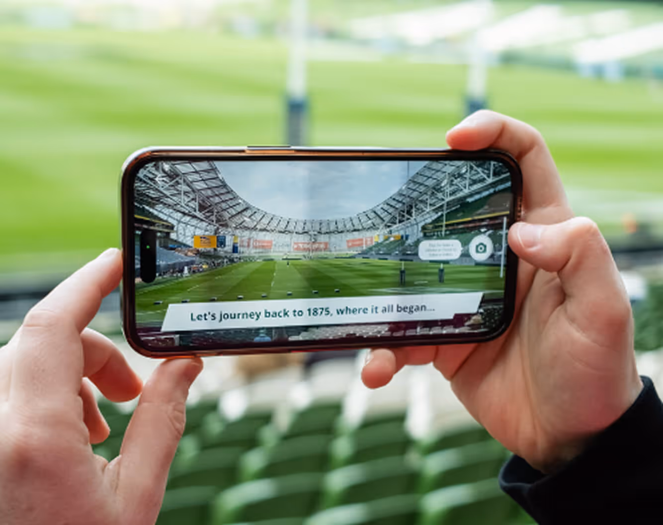 A person taking a picture of a stadium with a cell phone.