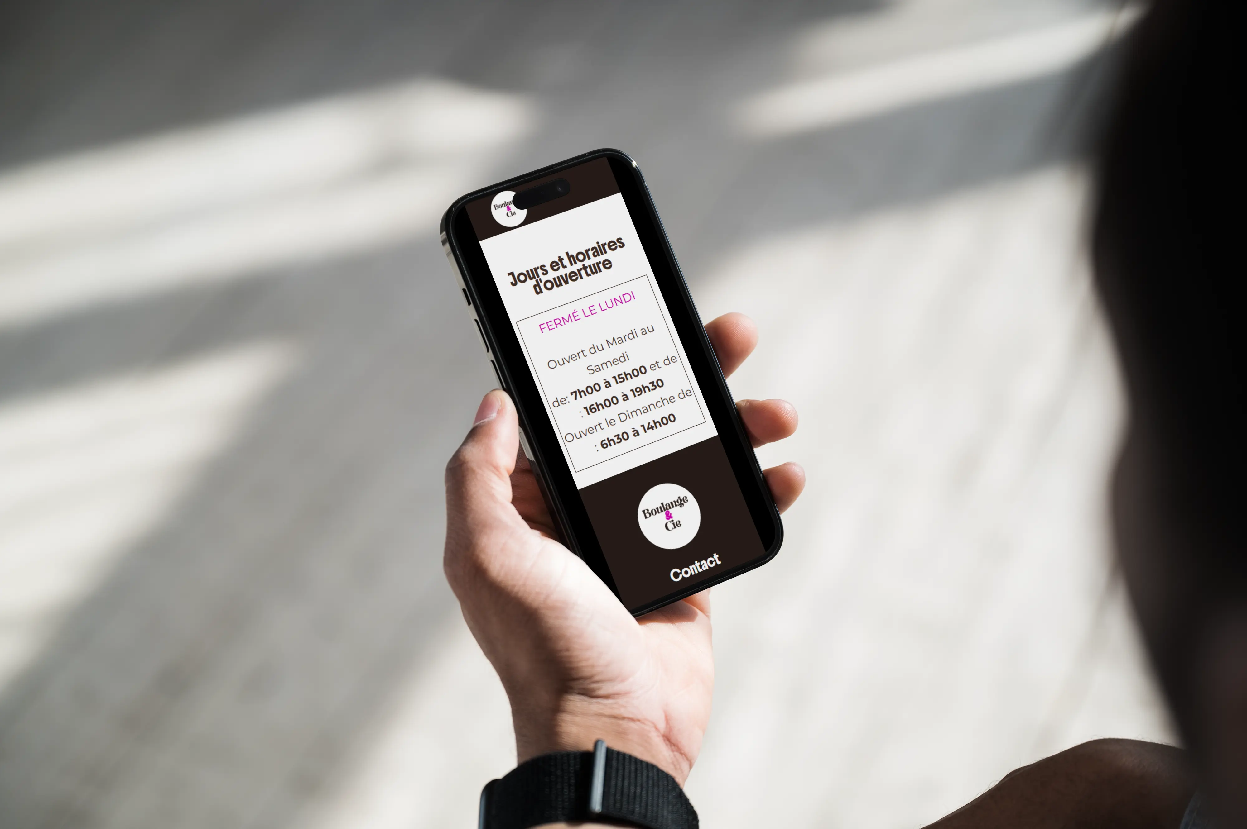 Un écran de smartphone affichant un site web de boulangerie, présentant les horaires d'ouverture de l'établissement