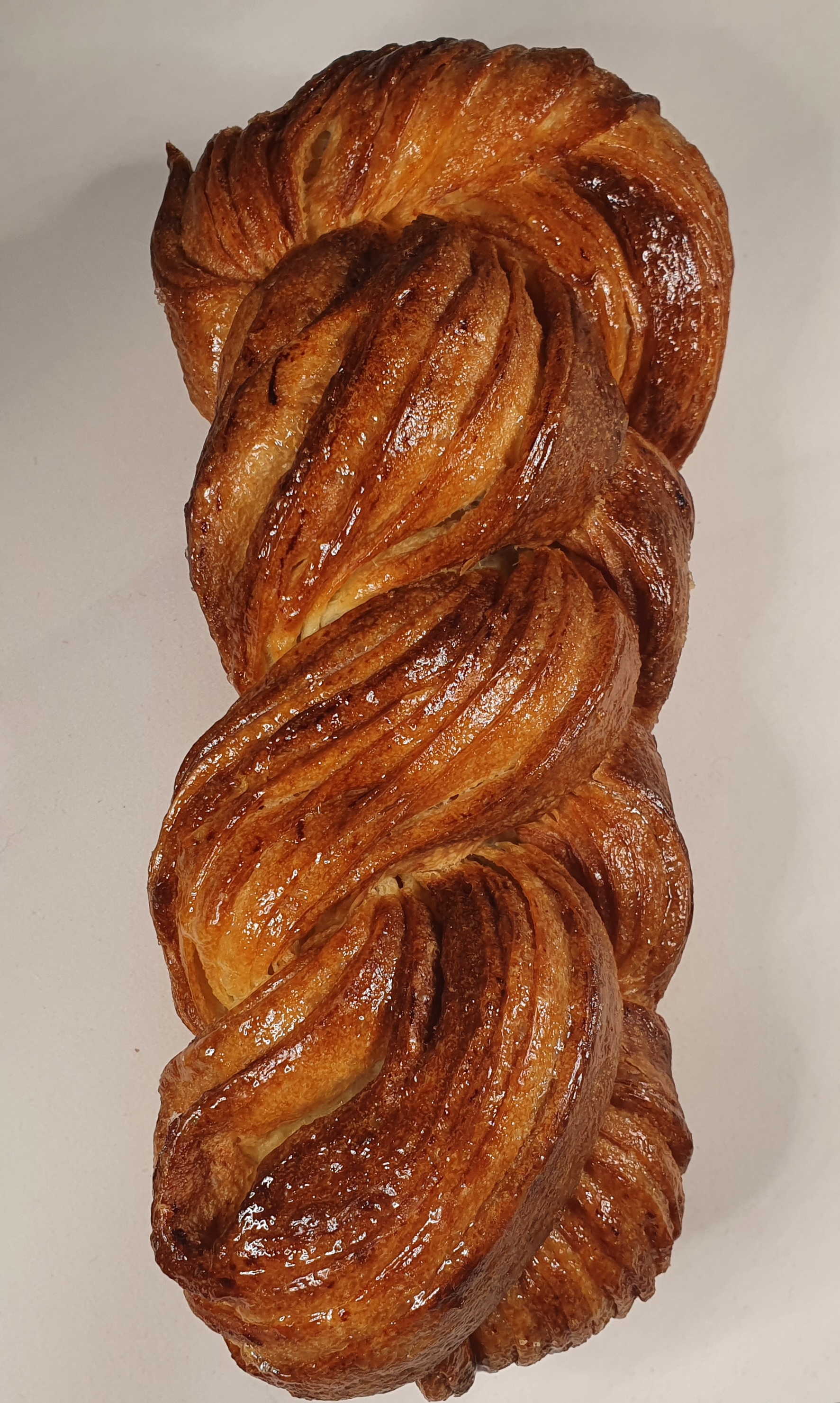 brioche tressée feuilletée présentée à la verticale sur un fond blanc