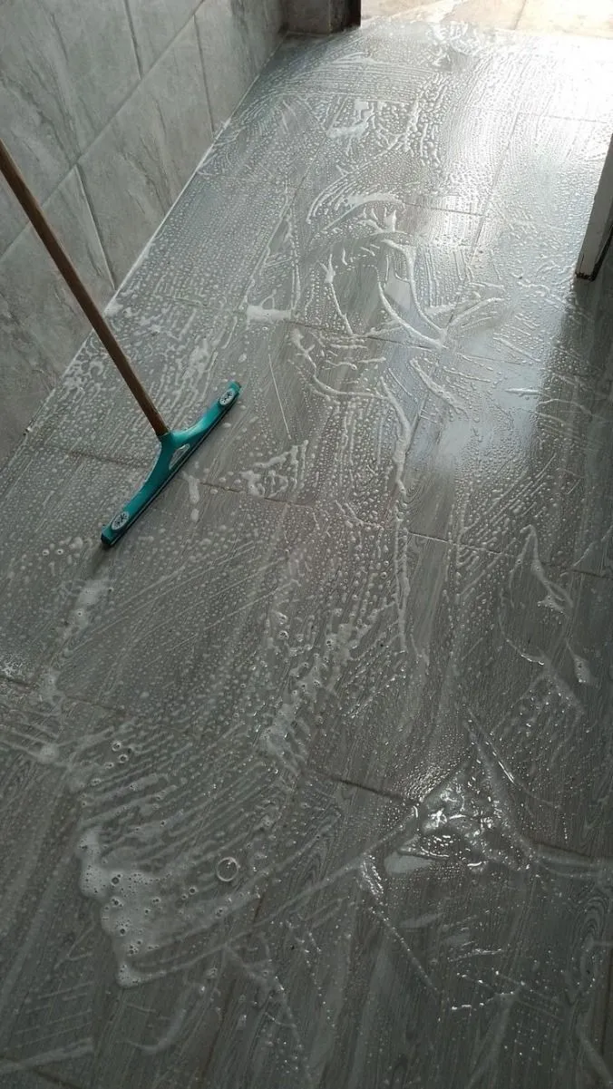 Un sol carrelé avec un balai à franges dessus.