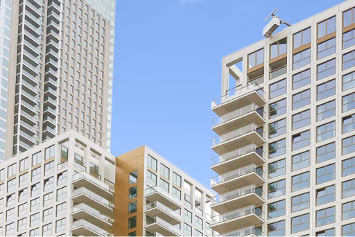 Moderne hoge gebouwen met veel balkons en ramen tegen een heldere blauwe lucht.