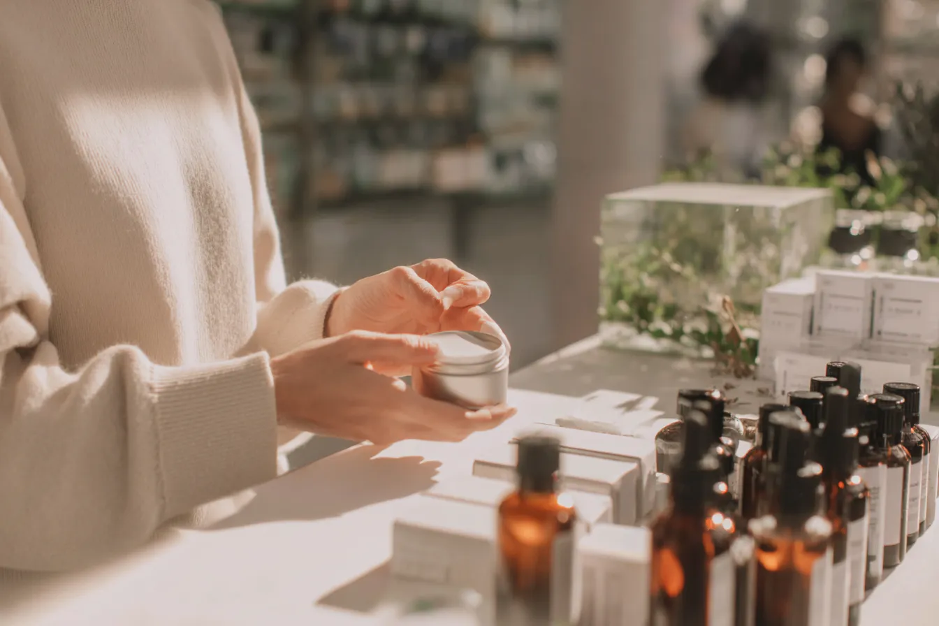 Eine Frau die mit dem Finger etwas Creme aus einer Dose nimmt