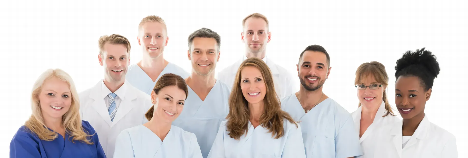 Smiling diverse group of nine healthcare professionals wearing scrubs and lab coats against a white background.