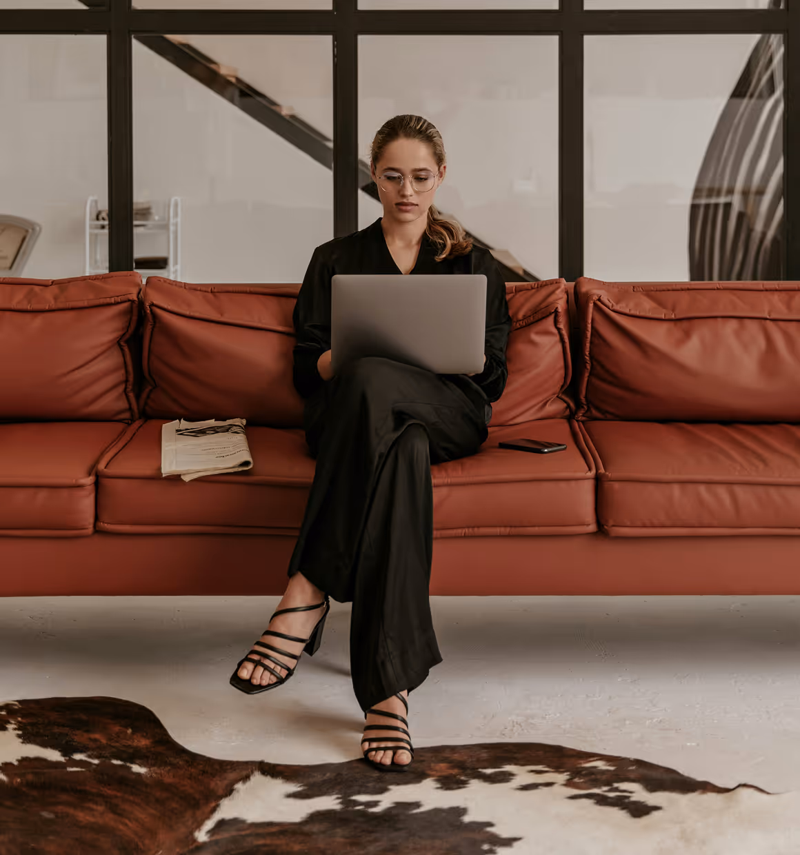 Girl sitting on sofas working on laptop.