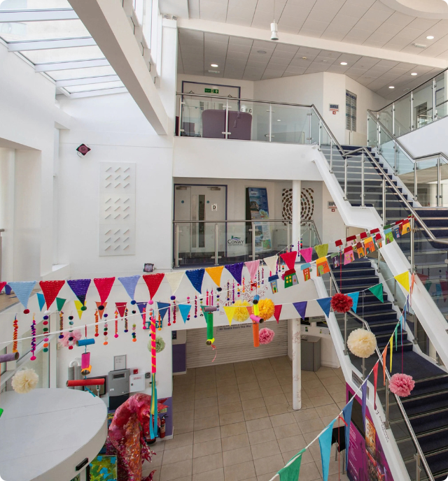 Interior shot of Venue Cymru - a white and glass building with colourful decorations and bunting