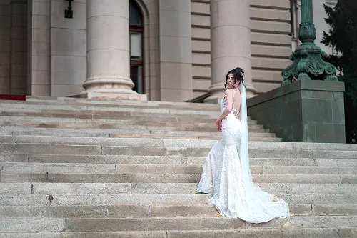 Mlada u dugoj beloj venčanici pozira na mermernim stepenicama – elegantan bridal portret – Fotograf Mihajlo – Niš