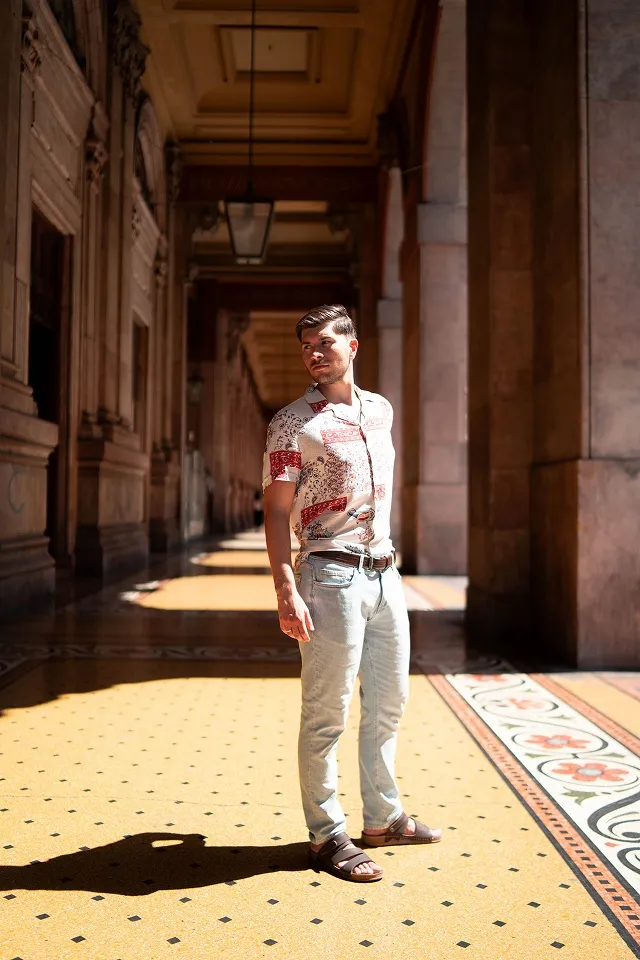 Stilski muški portret u prolazu sa klasičnom arhitekturom.