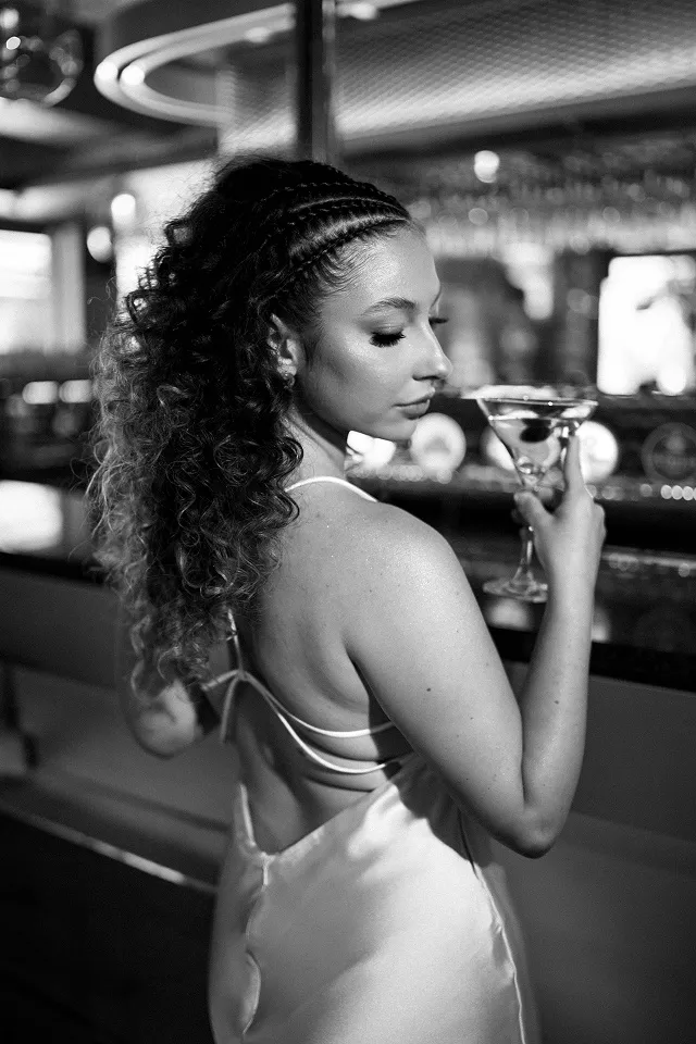 Elegantan portret devojke sa martini čašom u baru.