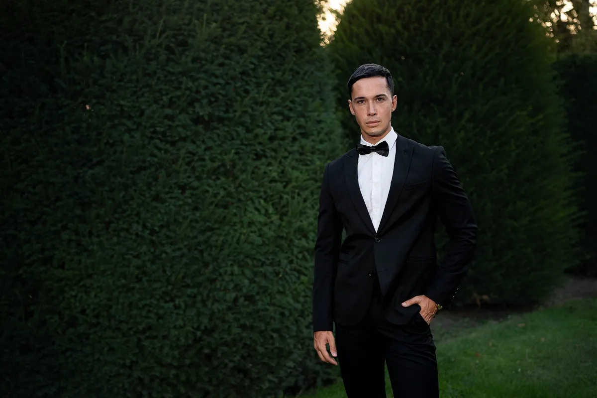 Elegantni portret muškarca u crnom odelu tokom priprema za svečani događaj.