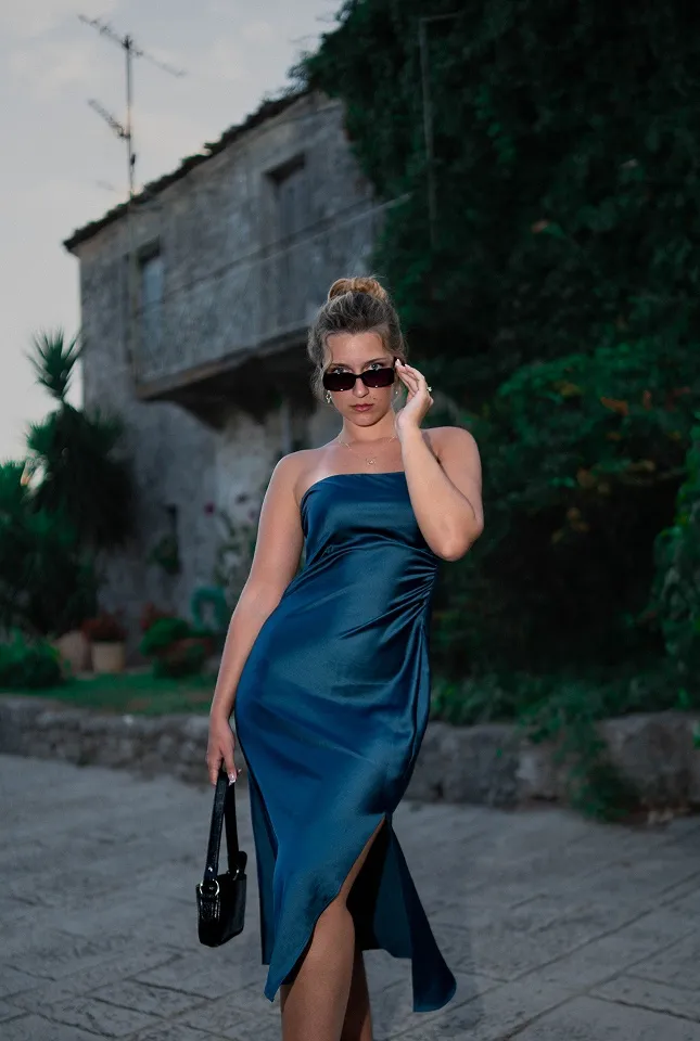 Portret devojke u plavoj haljini na kamenoj ulici sa mediteranskom arhitekturom u Italiji.