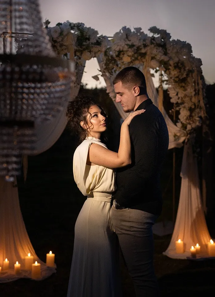 Romantičan večernji portret para u vinogradu blizu Leskovca, među svećama i dekoracijom.