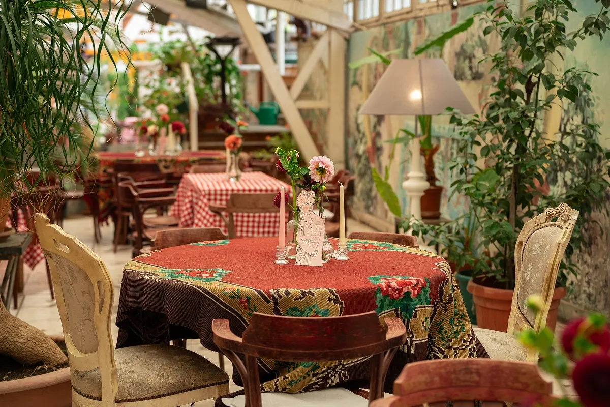 Uređena svečana sala sa rustičnim stolovima, cvećem i dekoracijom u toplim tonovima.