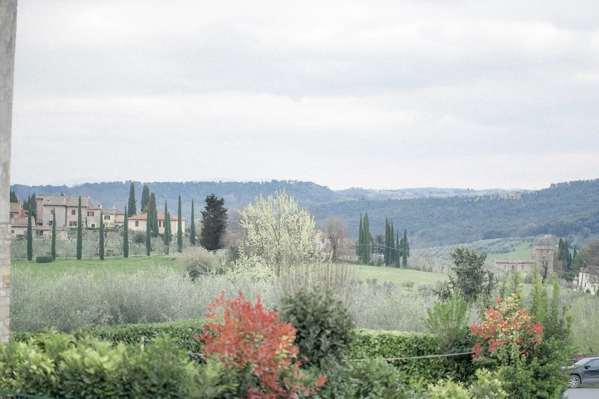 Pejzaž sa toskanskim brdima, čempresima i starim kamenim kućama u Italiji.