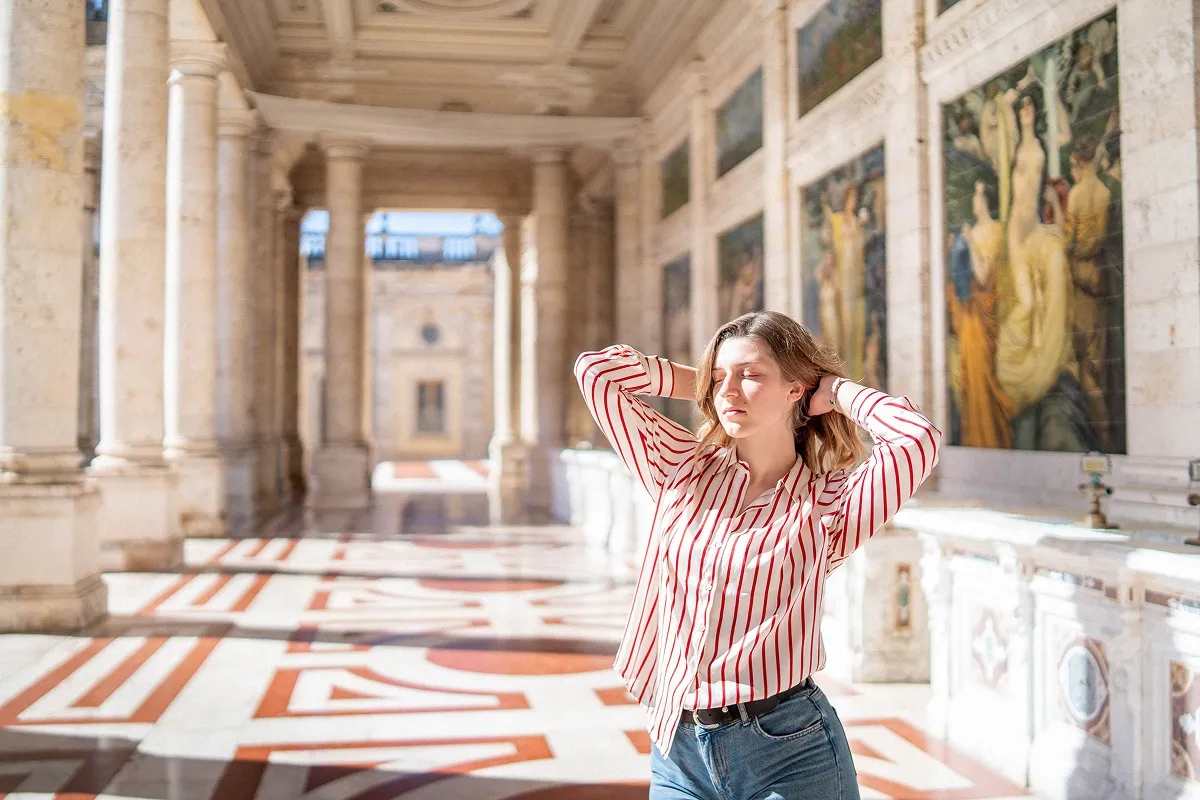 Portret devojke u prugastoj košulji u istorijskom holu Terme Tettuccio u Italiji, u sunčanoj i elegantnoj atmosferi.