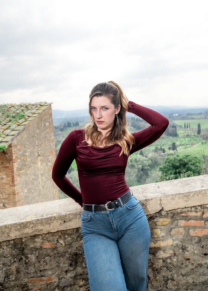 Portret devojke na kamenoj terasi sa toskanskim pejzažom u pozadini u Italiji.