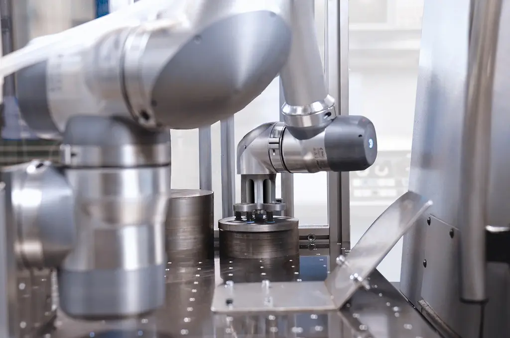 Close-up of robotic arms operating on metal components in an industrial manufacturing setting.