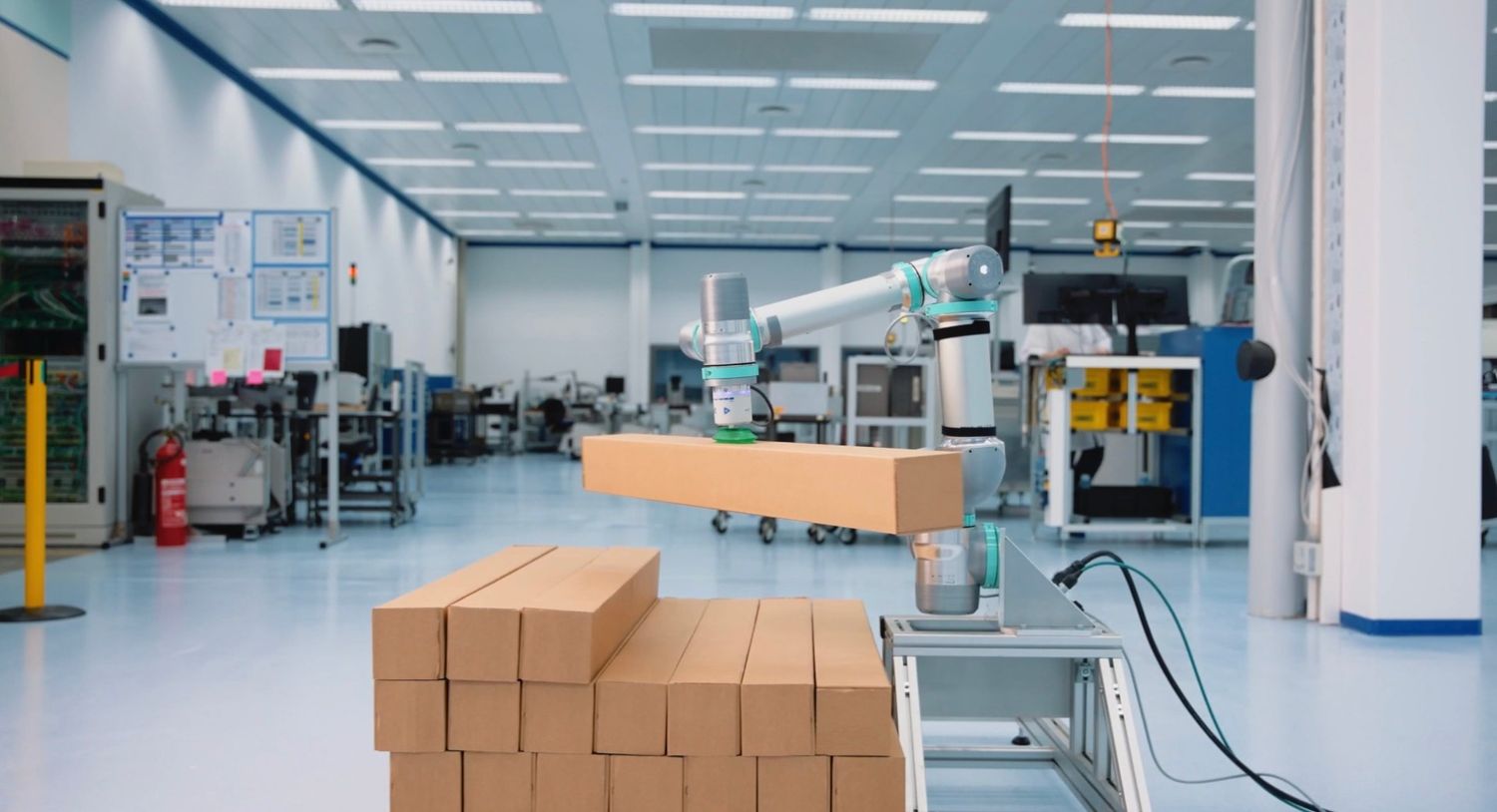 Ein Roboter zum Palettieren hebt einen Karton von einem Stapel in einer Lagerhalle und automatisiert so den Prozess des Stapelns von Waren auf Paletten.