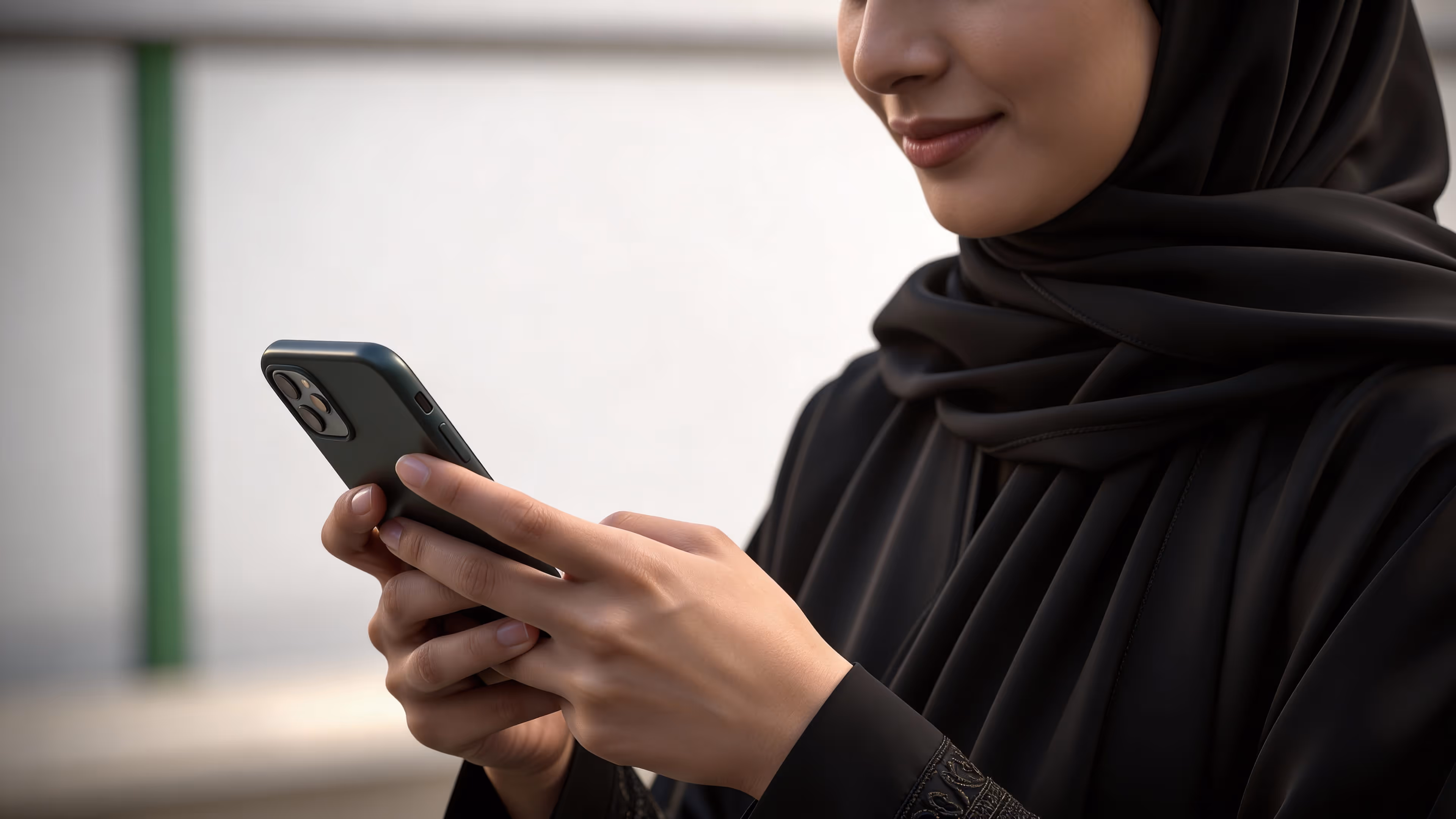 Woman in a black hijab using a smartphone, representing mobile access to financial or investment services.