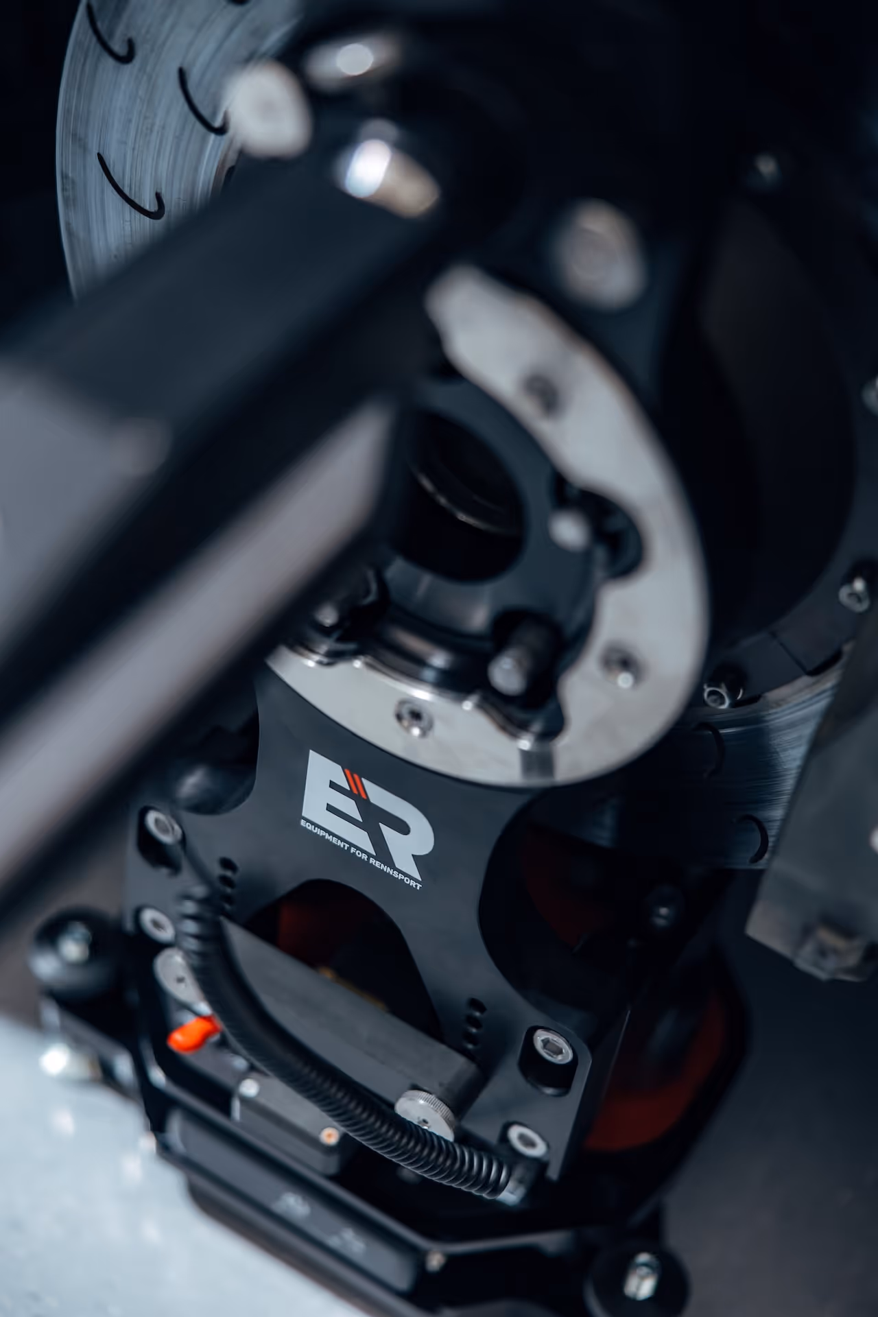 Close-up of whell alignment system PRO labeled 'ER Equipment for Rennsport' with metal components, digital display and wiring.